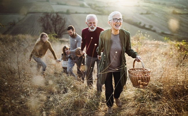 En familie med to ældre, en mor, far og to børn, der går i naturen og holder hinanden i hånden